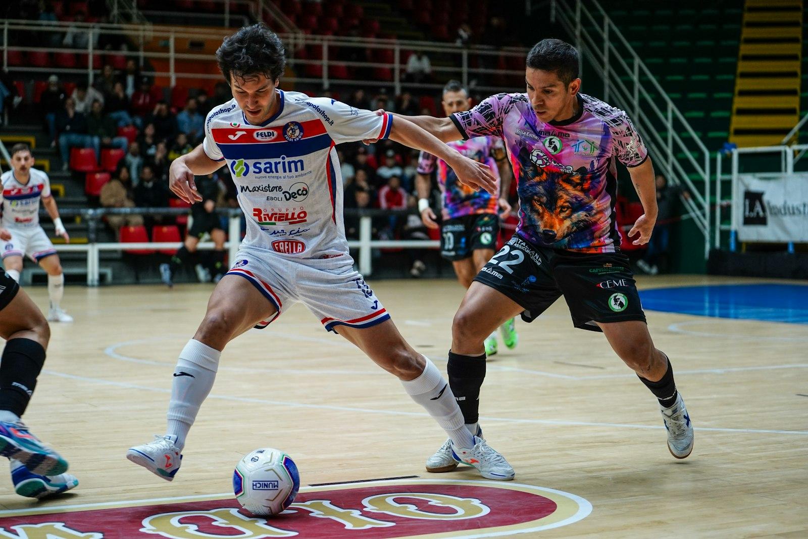 Two futsal players competing for the ball on an indoor court