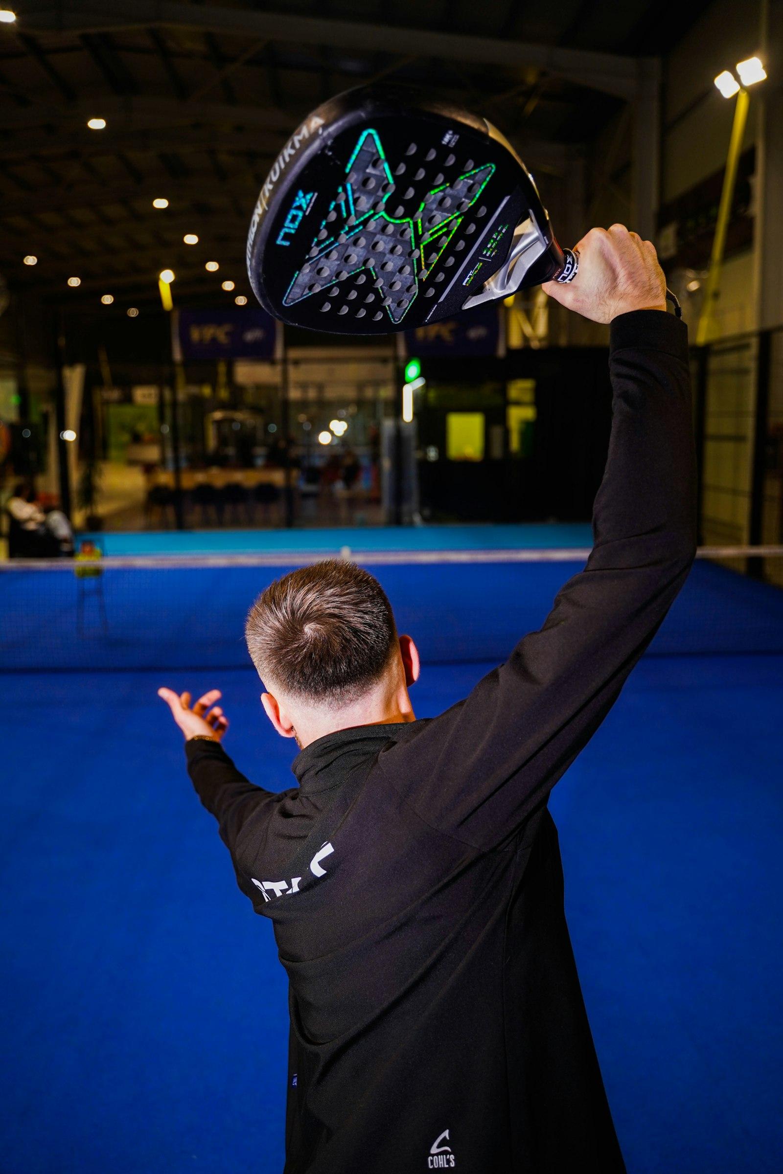 Padel player lining up an overhead shot on a blue court